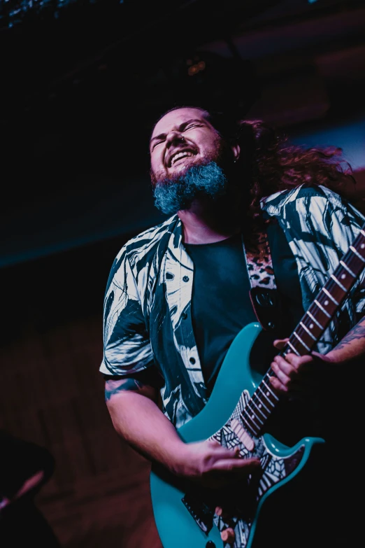 a man with long hair plays a blue guitar