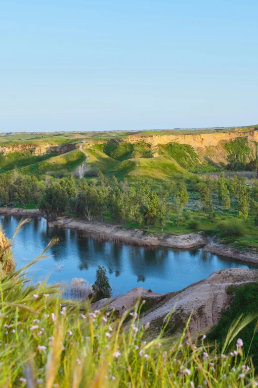 a lush green valley with a blue lake surrounded by water