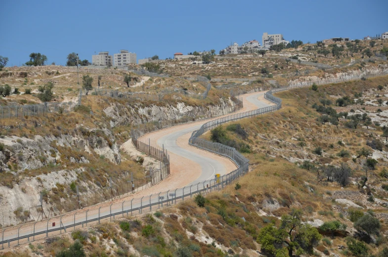 a curve of dirt road with buildings behind it