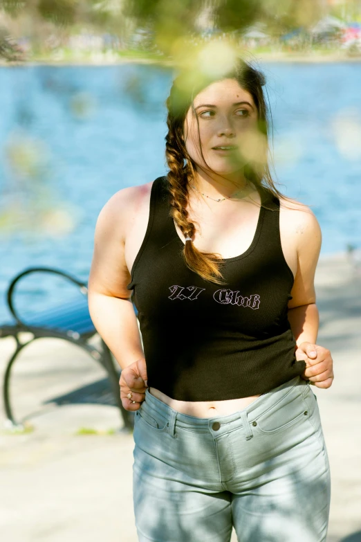 a young woman in short jeans is standing near the water