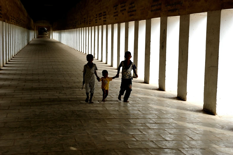 three people walk down a sidewalk with one holding onto the arms of another person