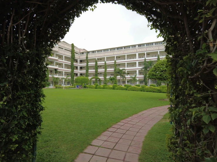 a path through the green grass between a grassy area and a building