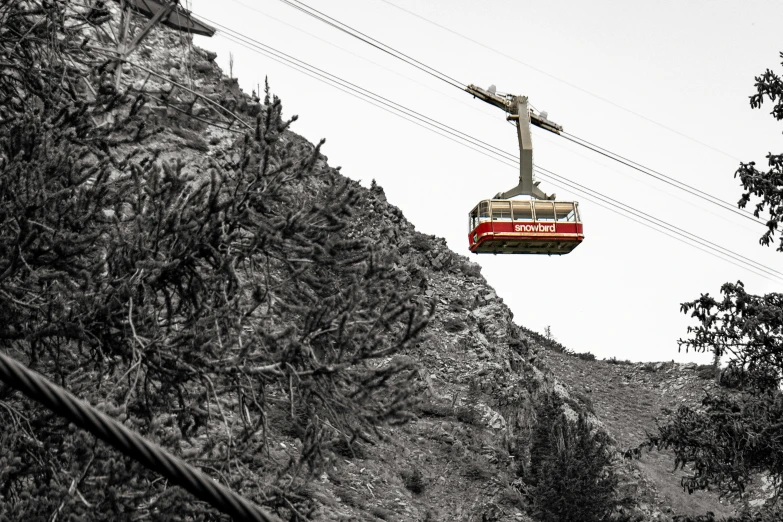 a gondola is suspended from a high mountain above some trees