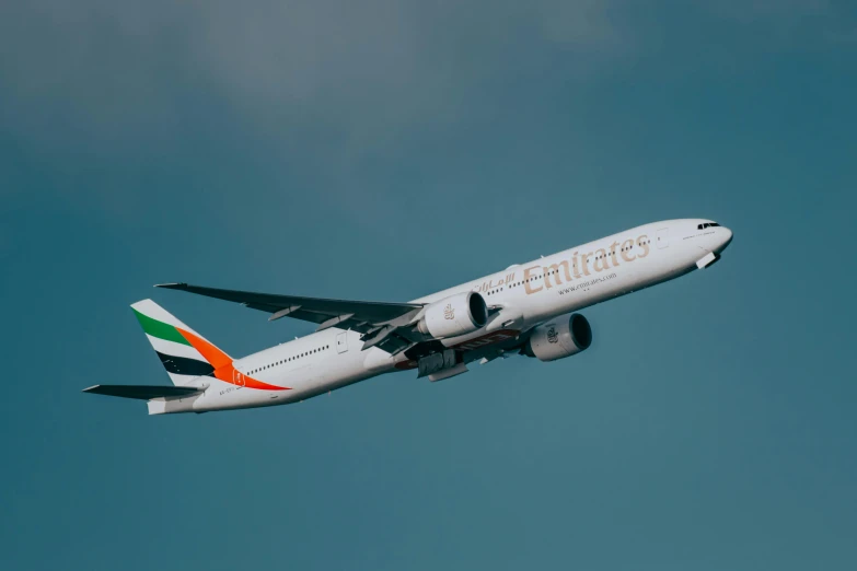 large white passenger airplane flying under a cloudy sky