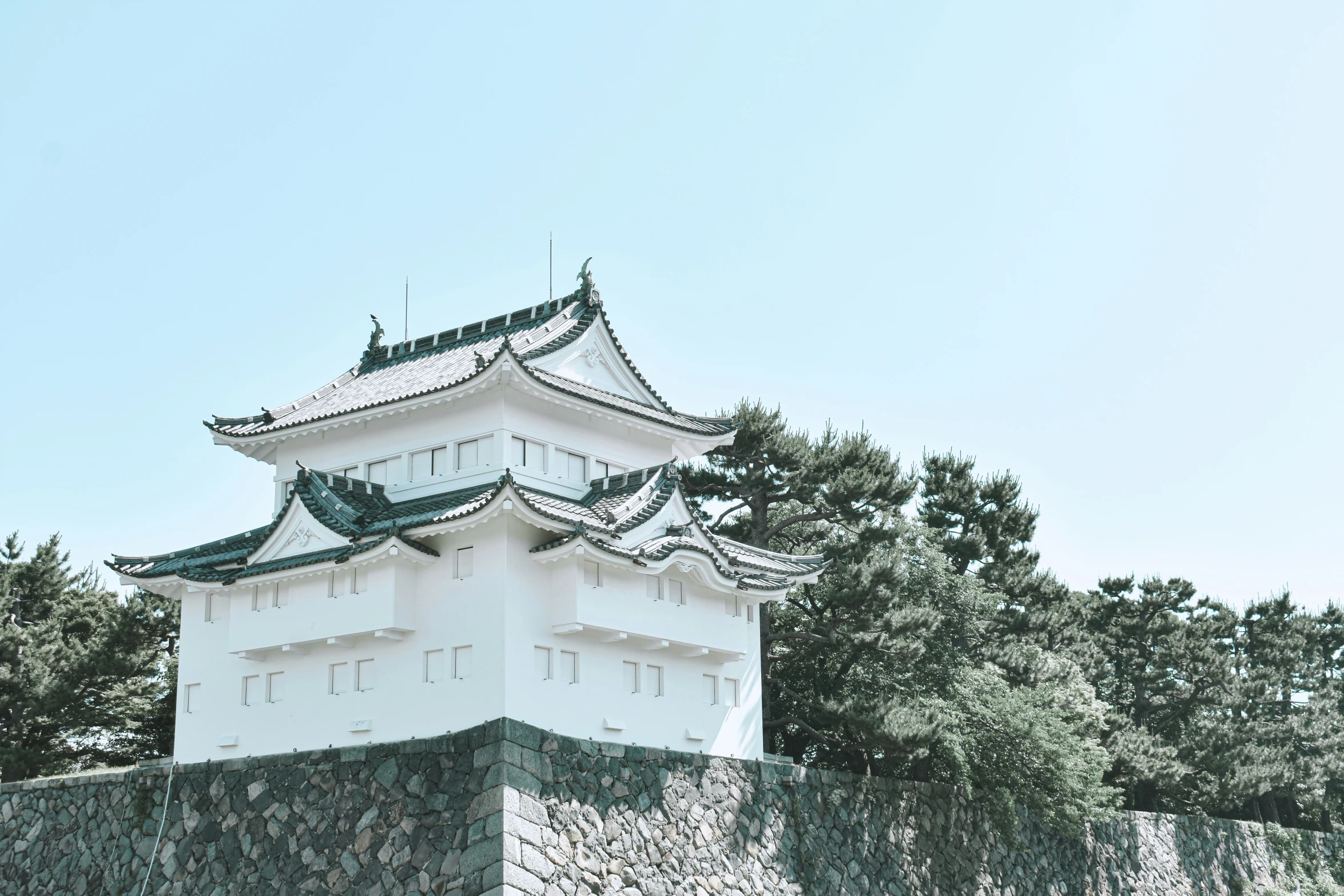 the tower of a japanese castle surrounded by rocks