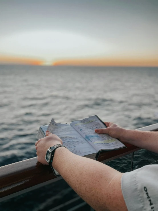 a person reads a map while on the deck of a boat