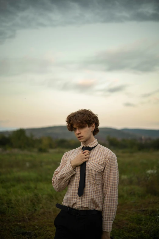 a man in dress shirt and tie standing in an open field