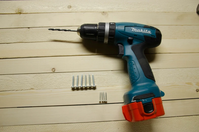 a cordless drill, hammer and screwdriver sitting on a wood board