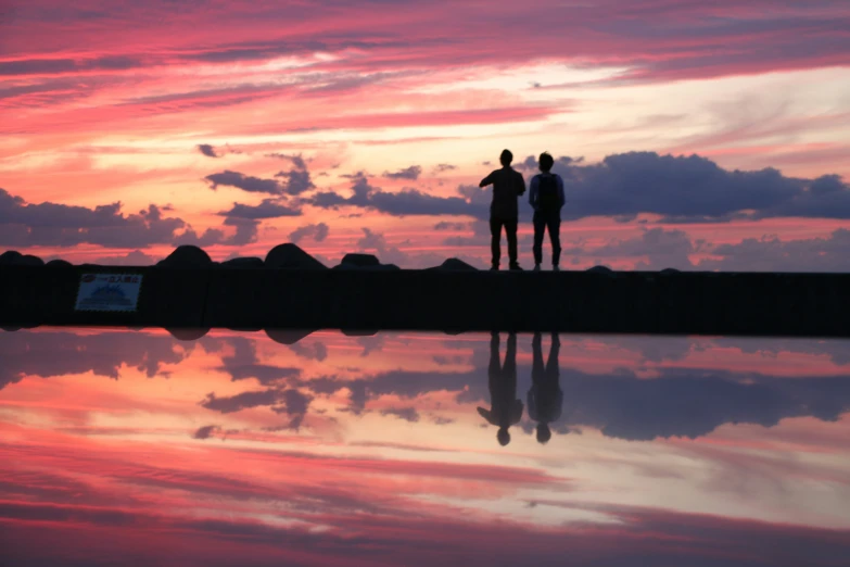 two people looking out at a sunset over the ocean