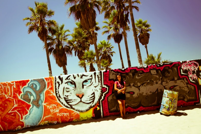 a woman stands in front of graffiti in front of palm trees