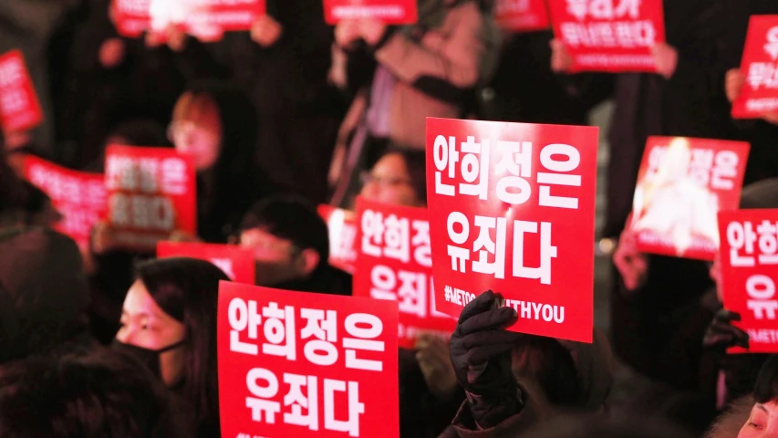 large group of people holding signs in korean words