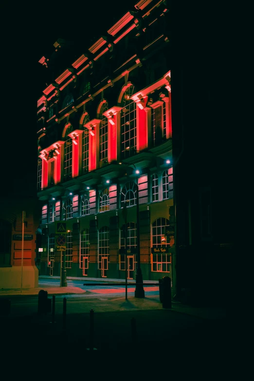 a large building at night with red lights on the windows