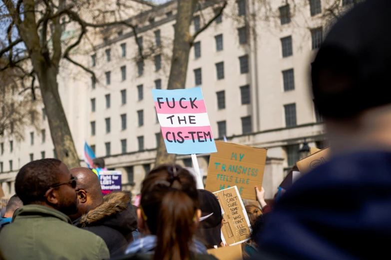 several people hold up signs and stand in a crowd