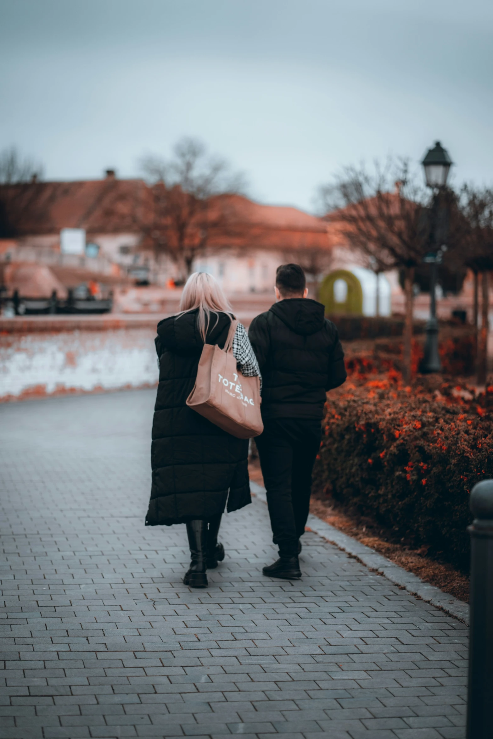 a man and woman walking down a street with a bag