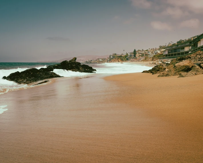 beach with houses on top of a mountain next to water