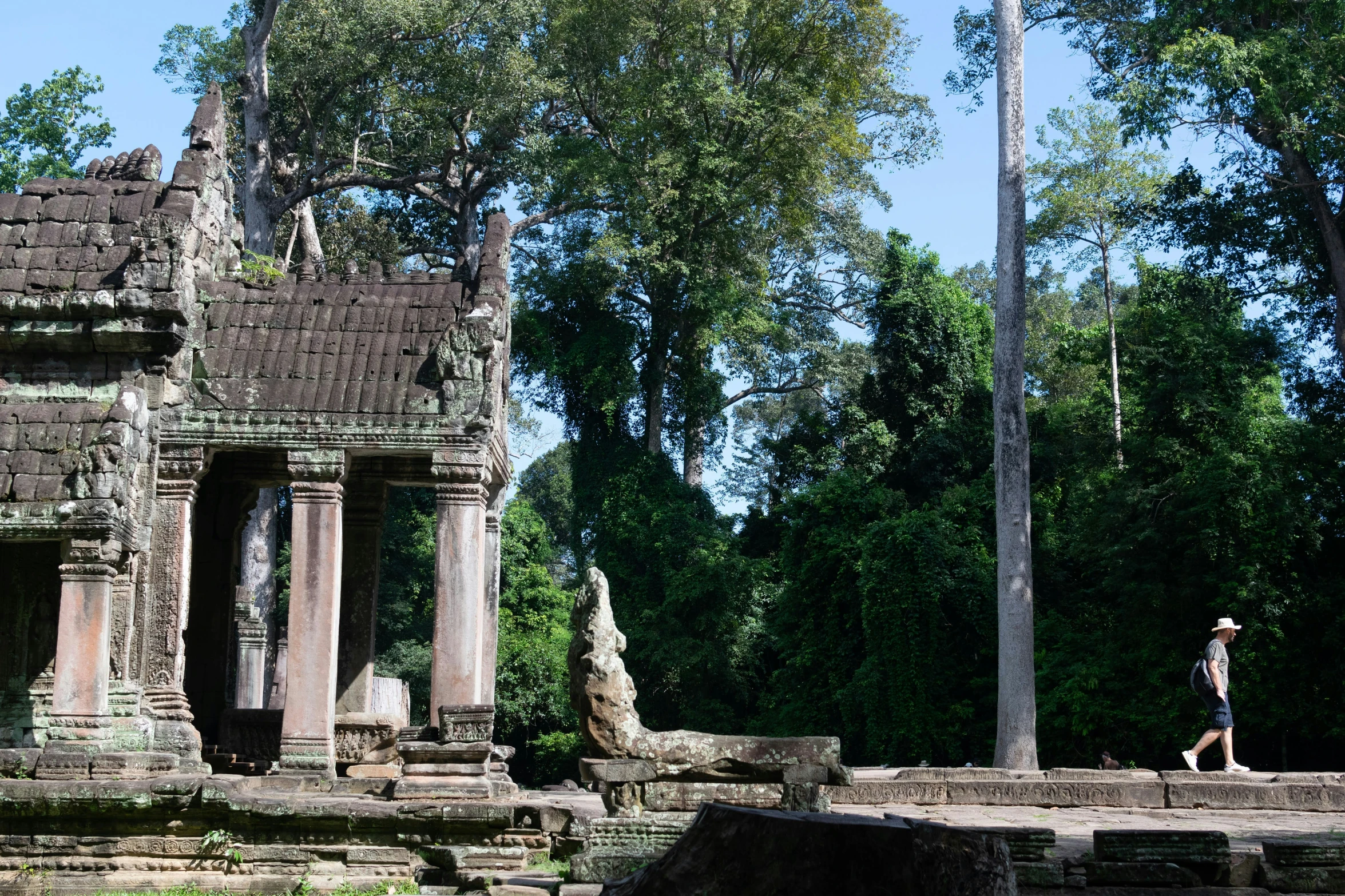 a person with luggage and wearing a hat walking by ruins