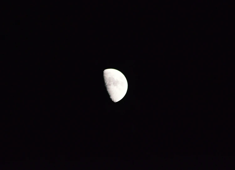 a moon is seen in the dark sky