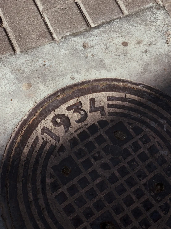 a metal sewer cover on the sidewalk