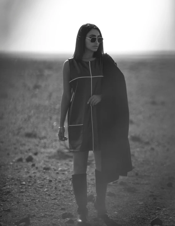 a woman standing in the desert with a scarf around her neck