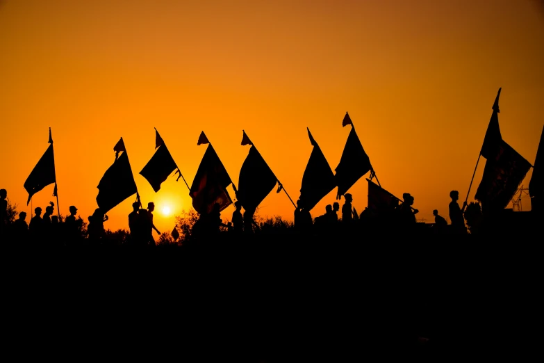 the sun sets on a beautiful yellow sky as people gather to watch the silhouettes of flags