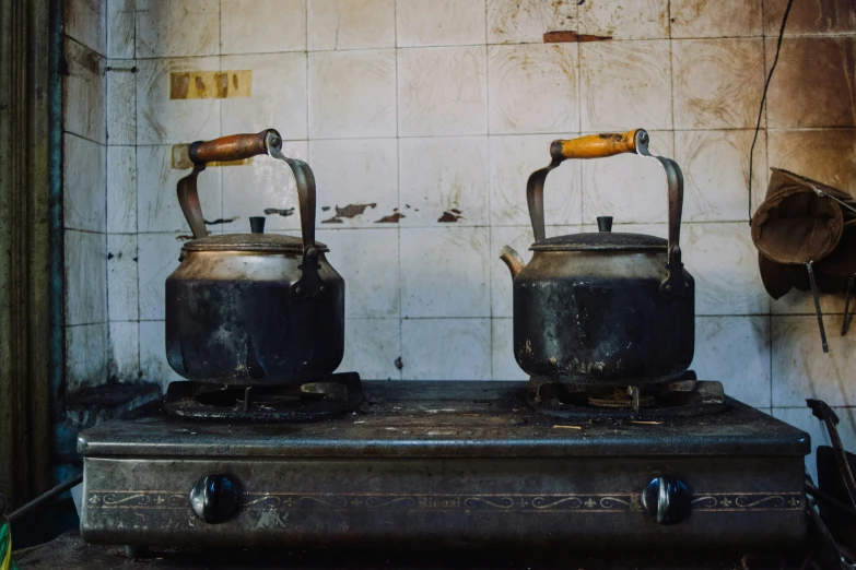 two kettles sitting on top of a stove next to a wall