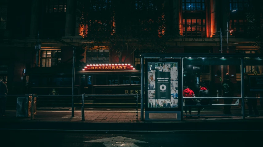 there is a bus stop that is on the street at night