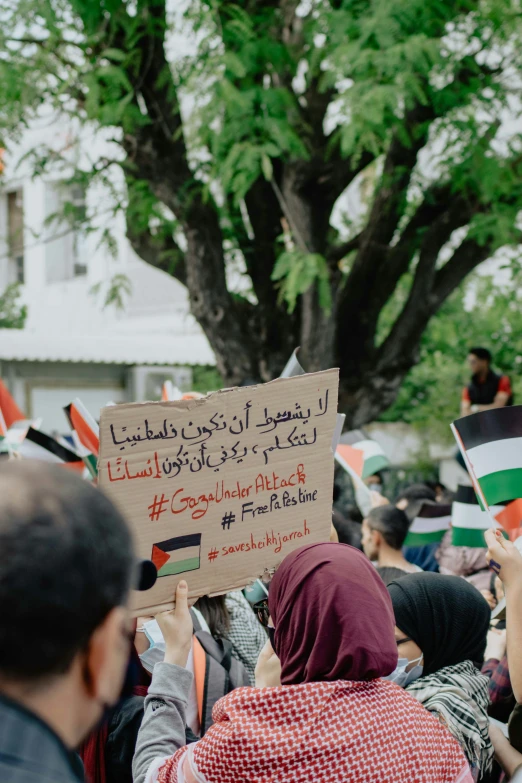 several people holding signs in a crowd outside a tree