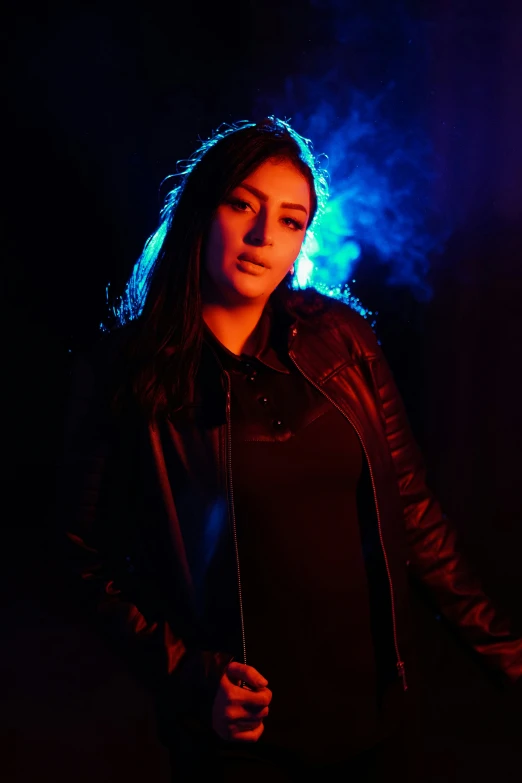 a girl in a black dress posing with a leather jacket on