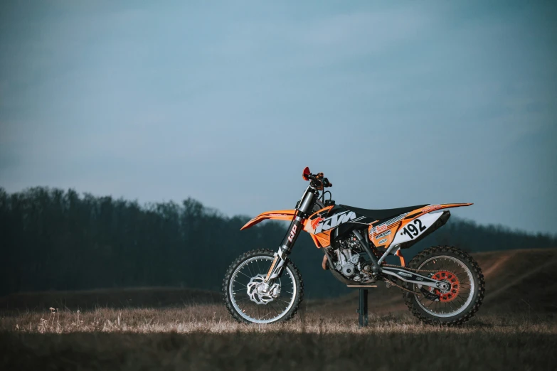 a dirt bike with an orange design in a field