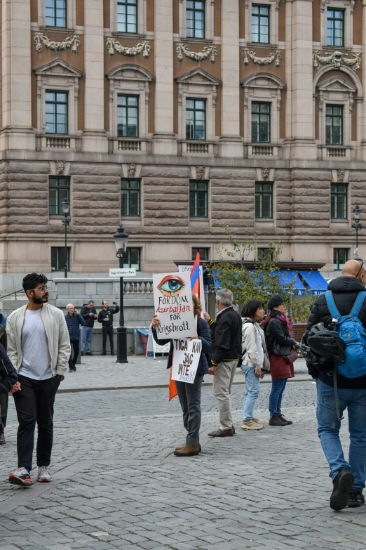 several people are walking on the sidewalk with signs