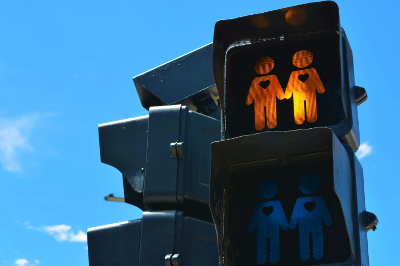 traffic lights, both depicting men and women, with sky in the background