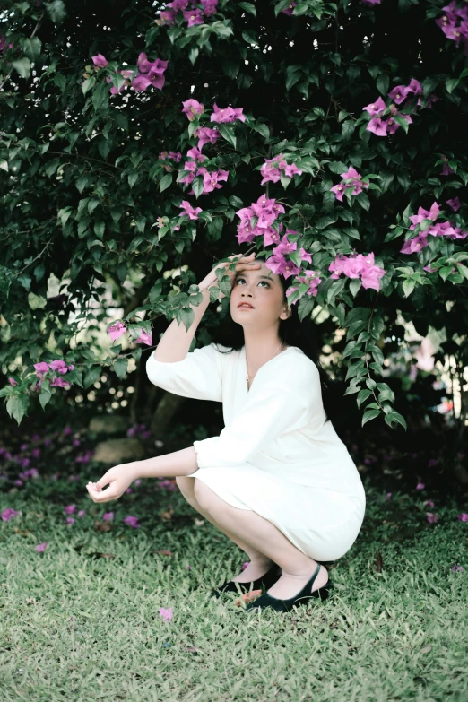 a woman is kneeling down by a bush