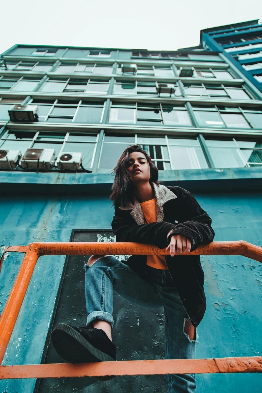 young woman sitting on top of large blue building