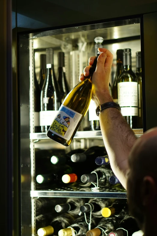 someone opens a bottle of wine from inside the glass cabinet