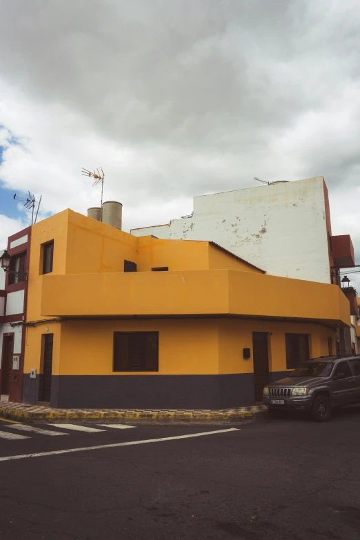 a yellow building has a sign that says to stop for the cars