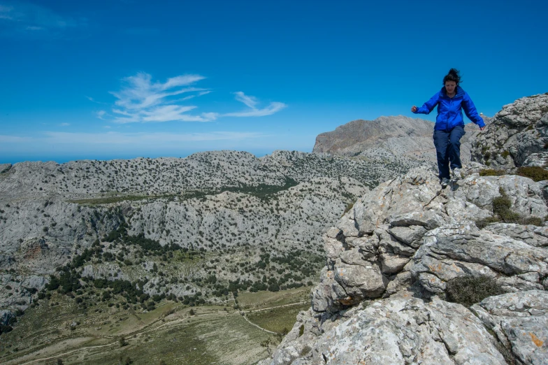 a woman stands on the side of a cliff above a valley