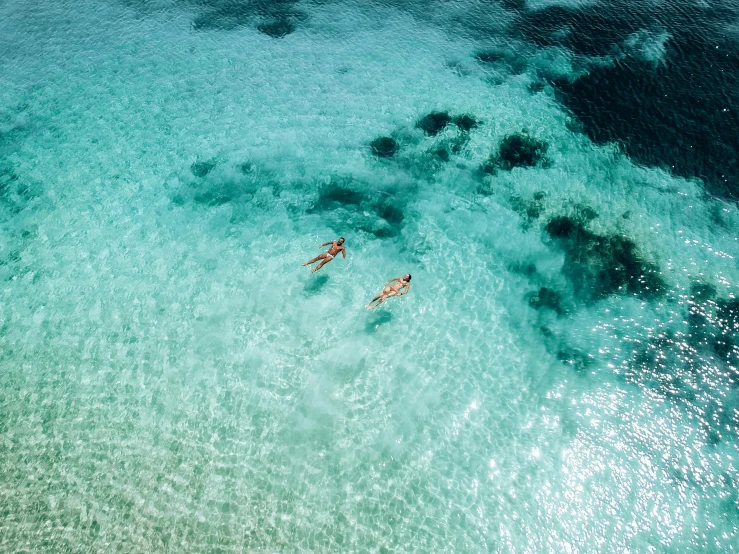 two people float down the ocean next to an island