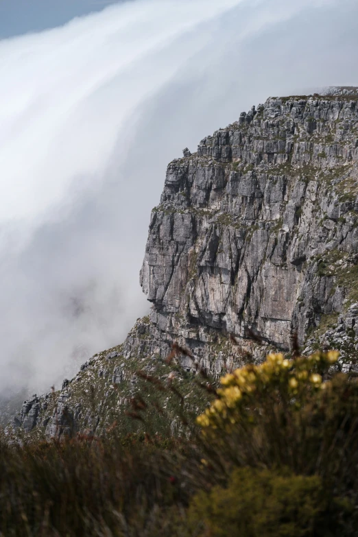 some clouds flying over a rocky mountain in a cloudy sky