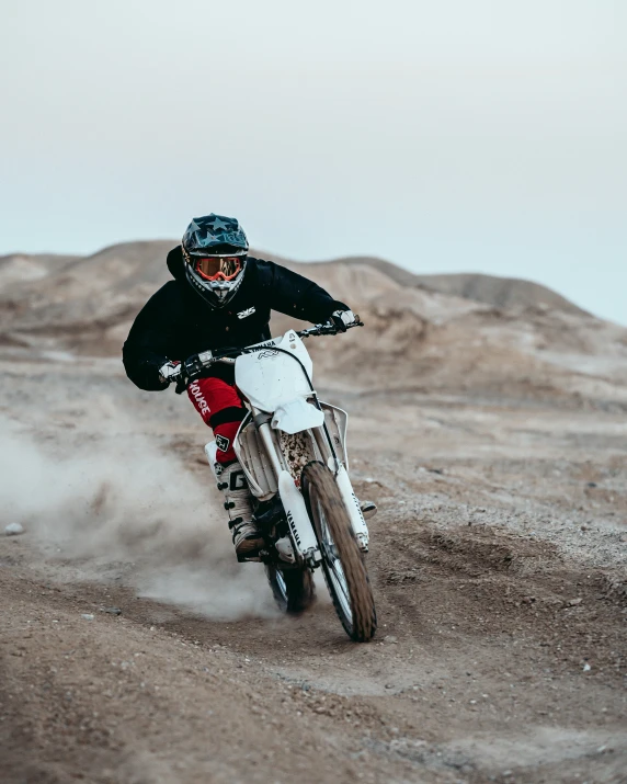 a man is doing tricks on a motorbike while driving in the desert