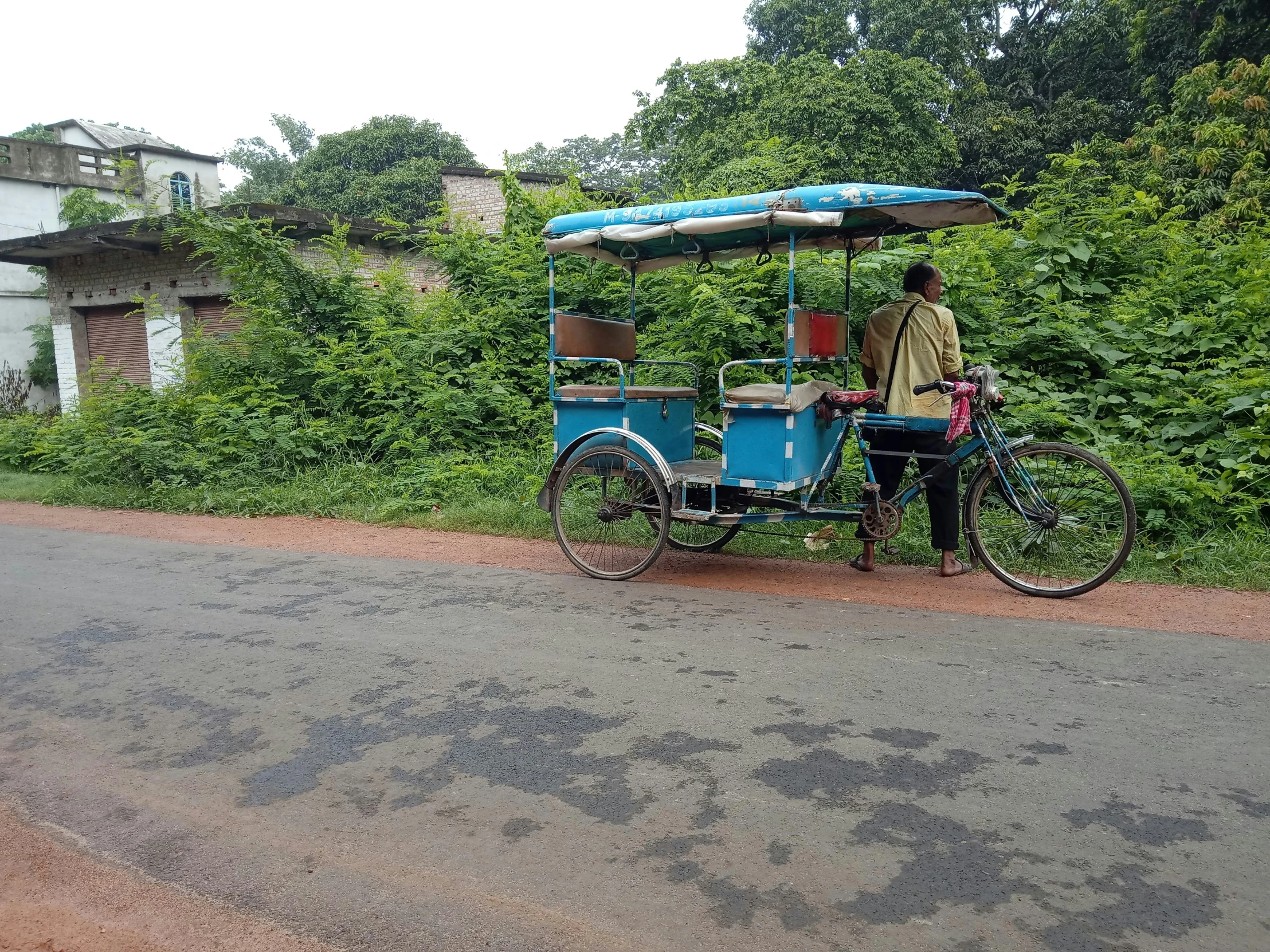 a man on a bike with a small blue cart