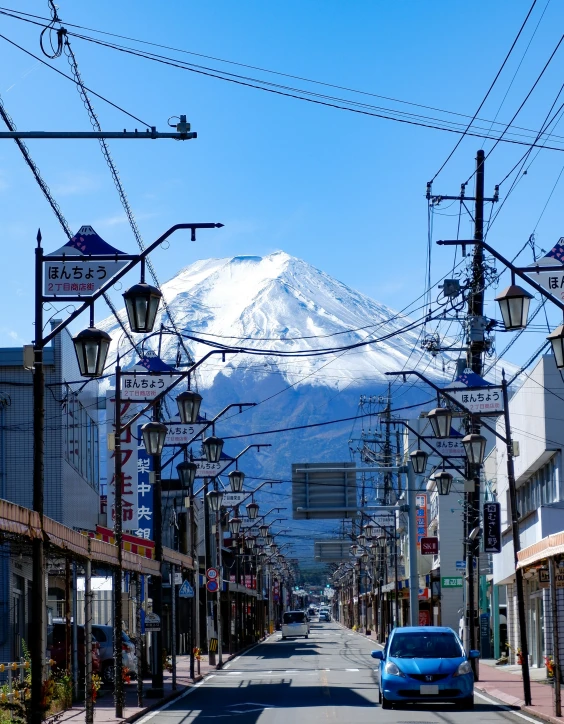 the car on the street looks so old, yet there is a mountain in the background