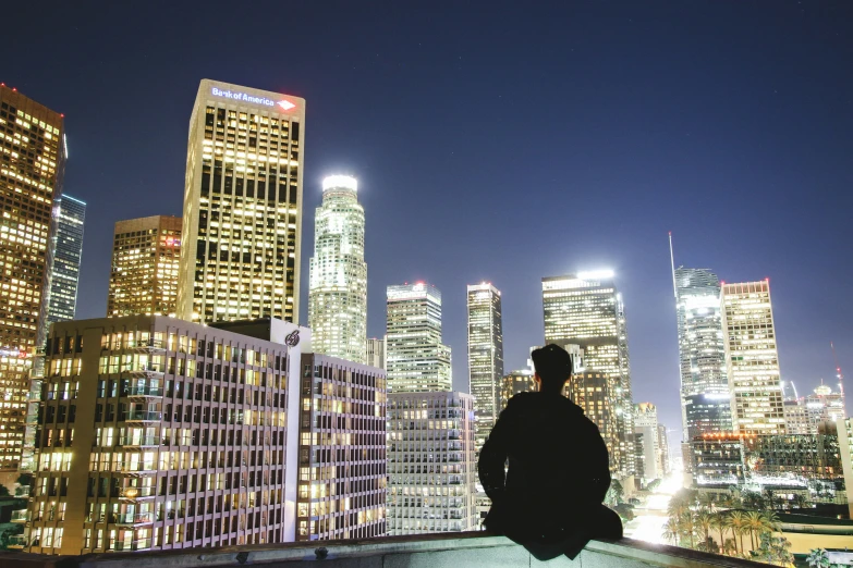 a man looking out over the city skyline at night