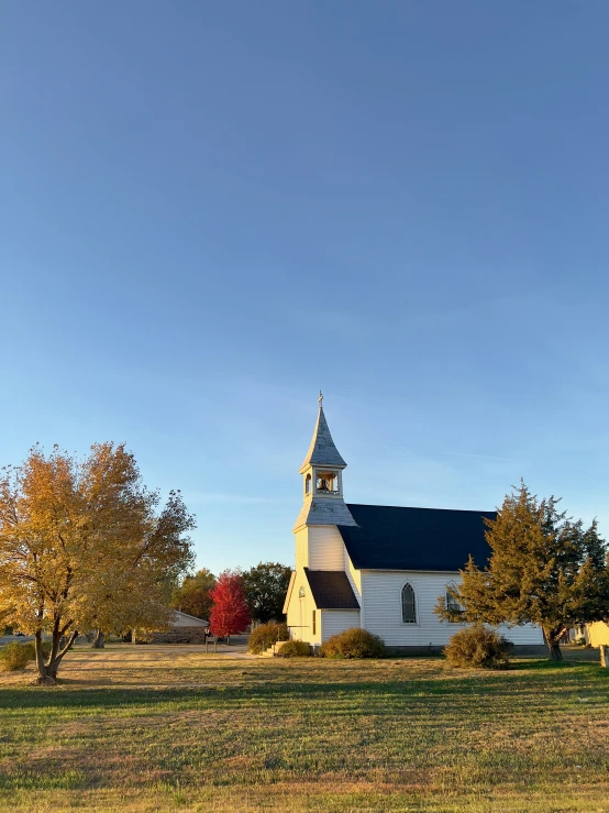 a church in the middle of a field with trees