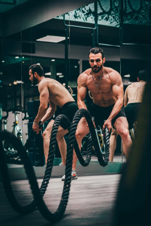 a man doing aerial exercise with ropes in the gym