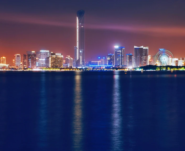 a city skyline seen at night with the lights reflecting on the water