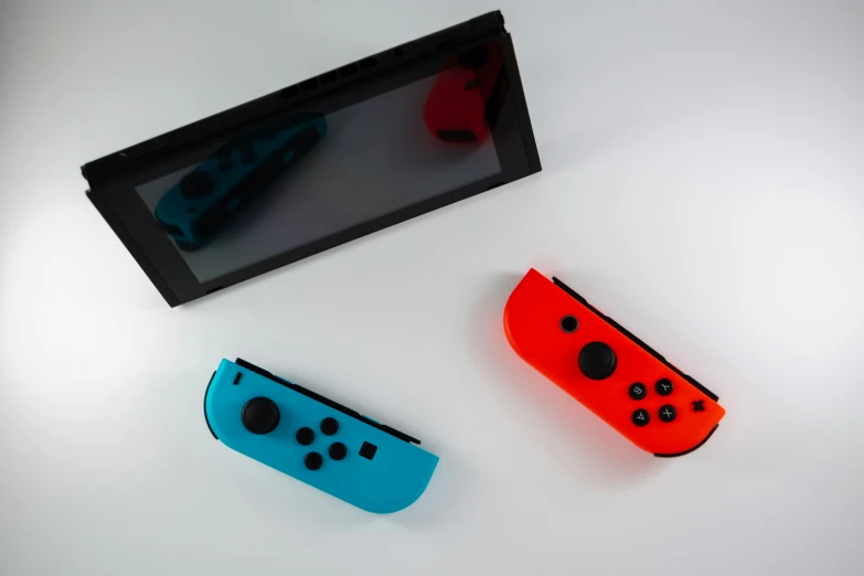 a couple of controllers laying next to a nintendo switch