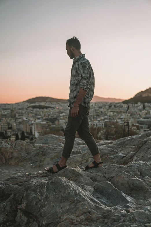 a person standing on top of a hill next to rocks