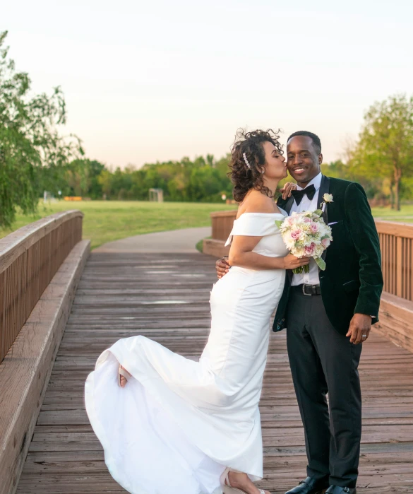 a bride and groom share an emce on a bridge