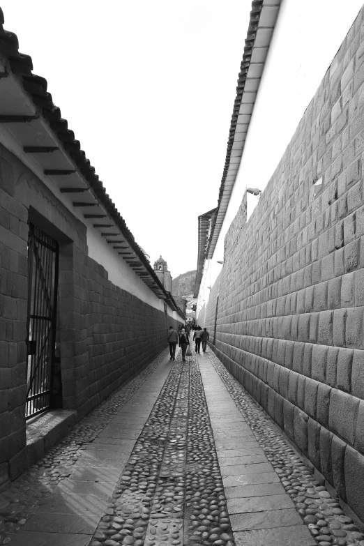 a long narrow brick street next to a wall