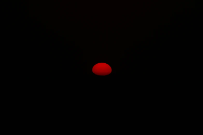 a red ball against a black sky that is not shining